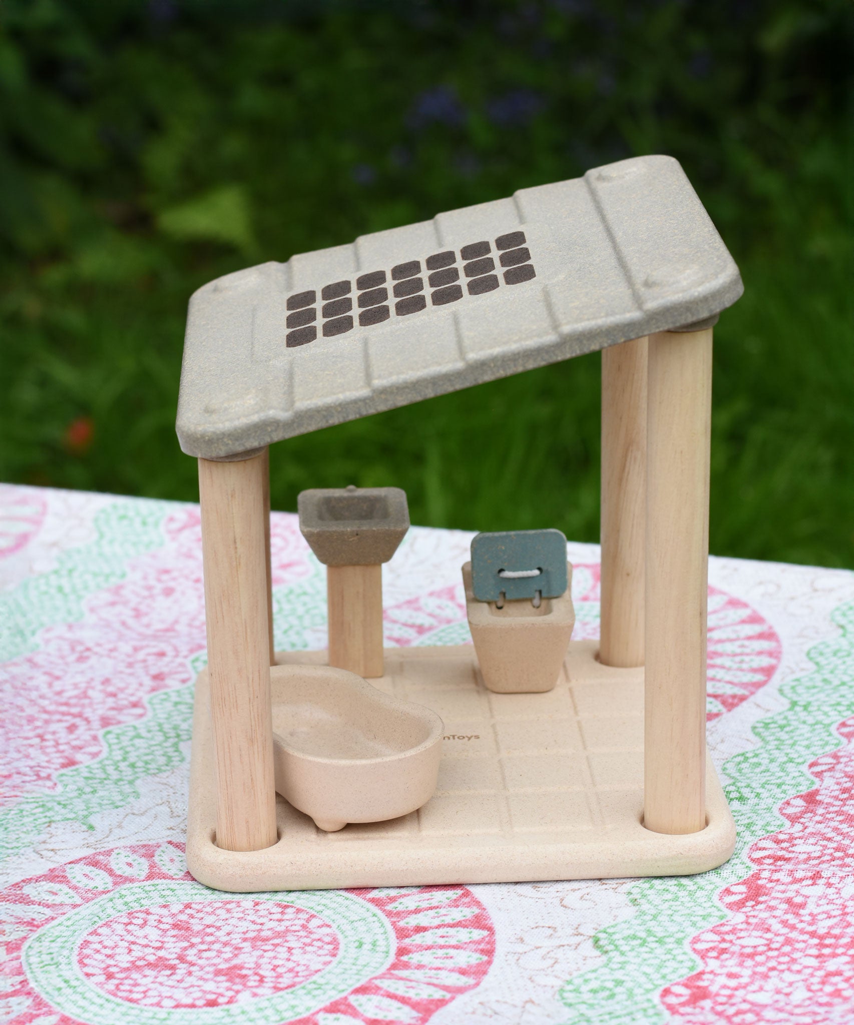 The PlanToys PlanSpace bathroom placed on a patterned tablecloth. The set can be used on it's own or with the other sets in the PlanSpace collection.