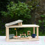 The Plan Toys PlanSpace living room set placed on a patterned cloth. The PlanSpace range is a collection of modular rooms to form a bugger dolls house.