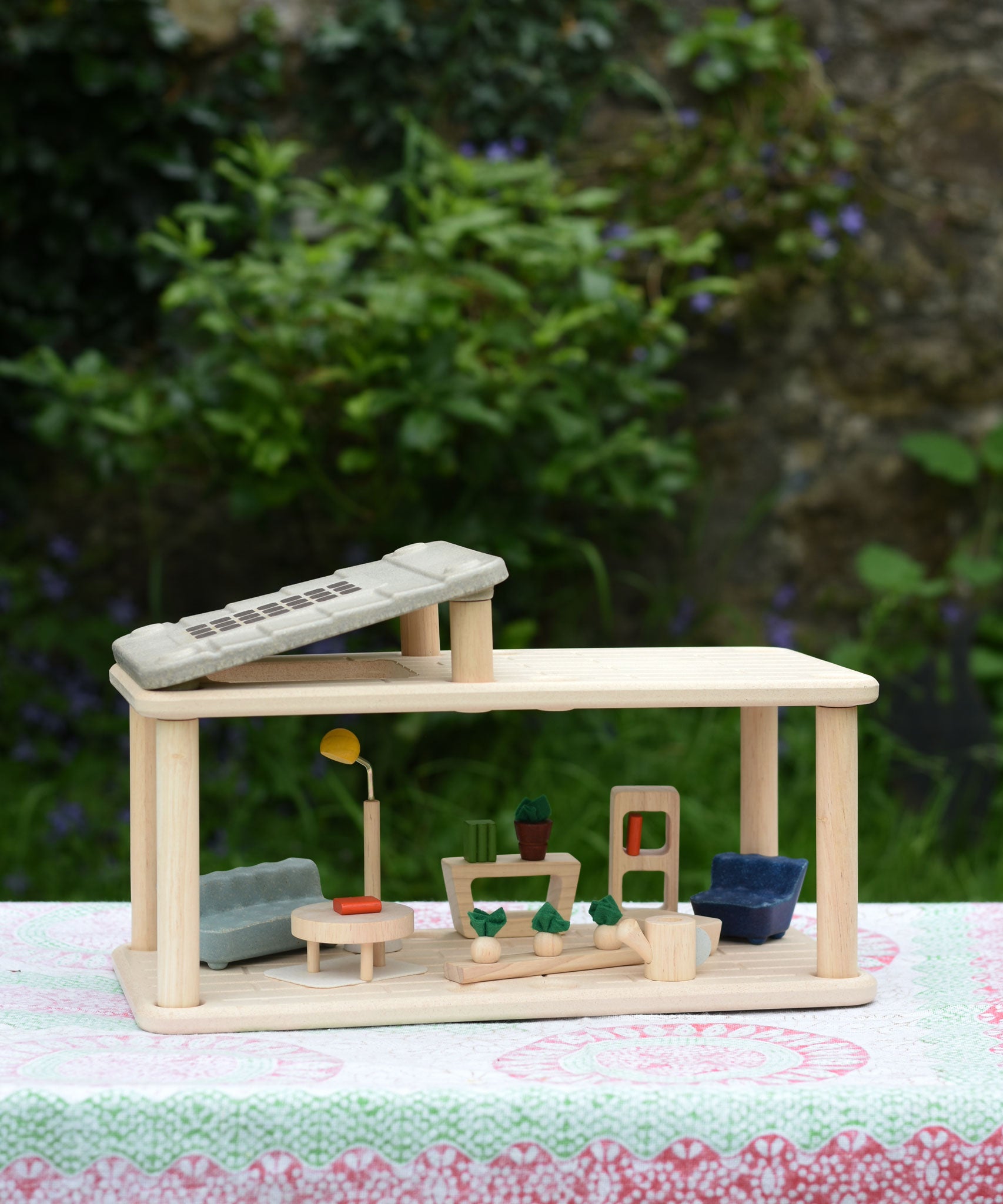 The Plan Toys PlanSpace living room set placed on a patterned cloth. The PlanSpace range is a collection of modular rooms to form a bugger dolls house.