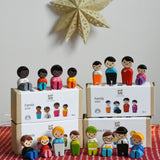 A collection of different PlanToys PlanWorld wooden doll family sets. The dolls are shown on and besides the boxes.