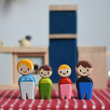 PlanToys PlanWorld wooden doll family with White Skin, Brown and Blonde Hair. The dolls have been placed in front of PlanToys dolls house furniture kitchen. 