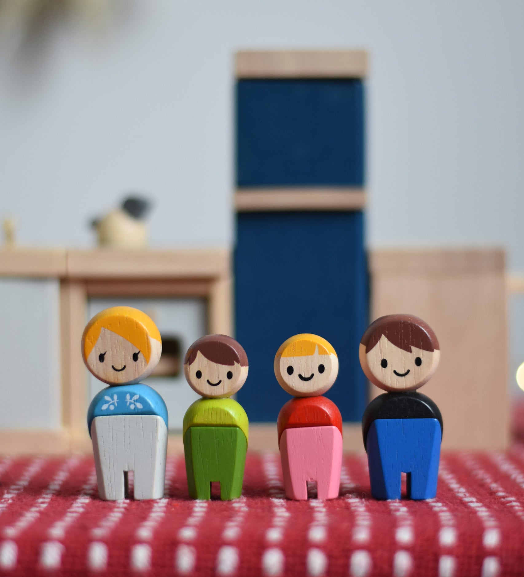 PlanToys PlanWorld wooden doll family with White Skin, Brown and Blonde Hair. The dolls have been placed in front of PlanToys dolls house furniture kitchen. 