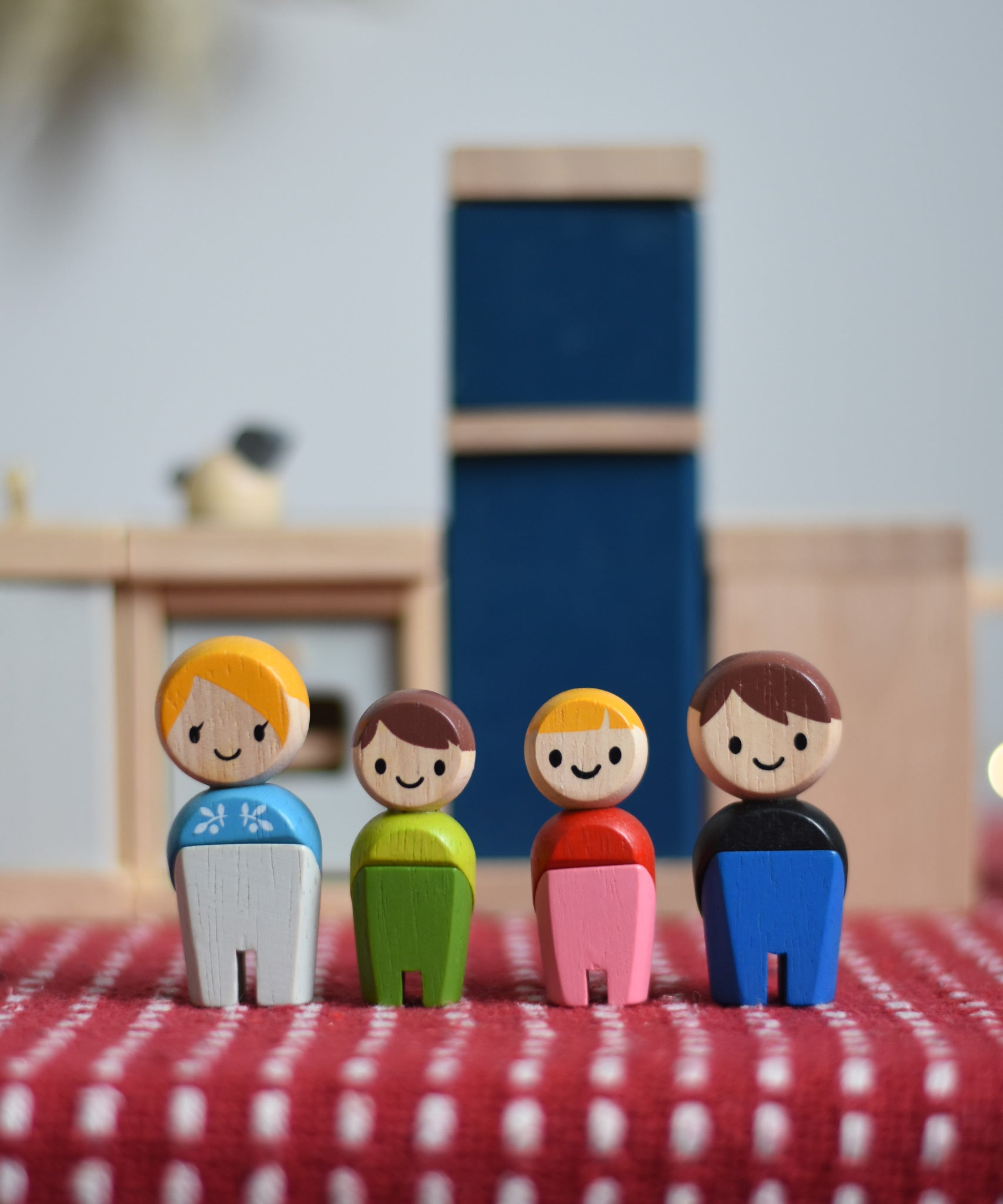 PlanToys PlanWorld wooden doll family with White Skin, Brown and Blonde Hair. The dolls have been placed in front of PlanToys dolls house furniture kitchen. 