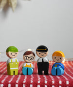 The PlanToys PlanWorld wooden doll service crew on a red surface, two are in a standing position and two are seated.