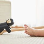 Close up of the PlanToys wooden gorilla pull along toy on a white carpet next to a child's feet
