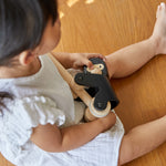 Close up of girl sat on a wooden floor holding the PlanToys plastic-free wooden climbing gorilla toy
