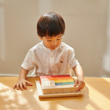 Young boy sorting the PlanToys coloured counting cube blocks on a wooden table