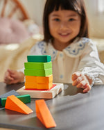 Close up of girl making a stack with the PlanToys plastic-free fraction blocks set