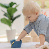 Baby playing with the PlanToys pop and drop wooden bucket baby posting toy putting their hand inside the bucket.