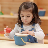 Toddler playing with the PlanToys pop and drop wooden bucket baby posting toy.