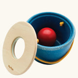 Toddler posting the red ball through the bucket lid