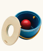 Toddler posting the red ball through the bucket lid