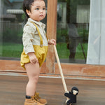 Young boy stood on a wooden floor holding the PlanToys solid wooden climbing gorilla toy