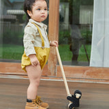 Young boy stood on a wooden floor holding the PlanToys solid wooden climbing gorilla toy