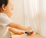 A baby reaching for the Plan Toys Wooden Pull & Grasp Baby Toy.