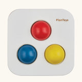 Overhead view of the PlanToys punch and drop bin wooden pounding toy with the red, yellow and blue balls resting in the slots on the top.