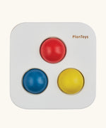 Overhead view of the PlanToys punch and drop bin wooden pounding toy with the red, yellow and blue balls resting in the slots on the top.