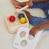 Overhead view of a child playing with the PlanToys punch and drop bin wooden pounding toy, taking the lid off the bin.
