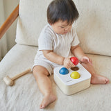 Baby playing with the PlanToys punch and drop bin wooden pounding toy.