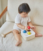 Baby playing with the PlanToys punch and drop bin wooden pounding toy.