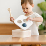 Child lifting the lid off the PlanToys punch and drop bin wooden pounding toy.