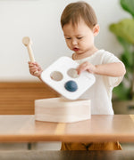 Child lifting the lid off the PlanToys punch and drop bin wooden pounding toy.