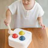 Child playing with the PlanToys punch and drop bin wooden pounding toy. Hammering the red ball into the bin through a slot on the lid.