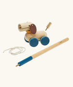 PlanToys push and pull puppy wooden toy. Wooden dog with brown ears and blue wheels that comes with a sting and a screw in stick so that it can be either pulled or pushed along. 
