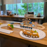 PlanToys wooden trains and blocks placed around the wooden train tracks and rubber railway road sets.