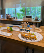 PlanToys wooden trains and blocks placed around the wooden train tracks and rubber railway road sets.