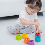 A child sitting on the floor in front of a sofa playing with the Plan Toys Bee Hives Rainbow set. 