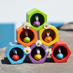 The PlanToys rainbow bee and bee hives set stacked up in a 3, 2, 1 formation. All the bees are in the hives daisies have been placed in-between the hives. 