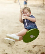 Child swinging outside on the PlanToys Saucer Disc Swing. 