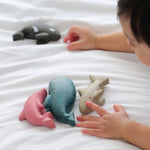 A close up of a child's hands playing with the figures from the PlanToys Sea Life Set. 