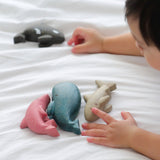 A close up of a child's hands playing with the figures from the PlanToys Sea Life Set. 