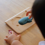 PlanToys Sea Life Puzzle with the pieces shown in the puzzle base on a wooden table. 