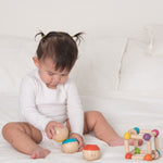 A baby playing with the Plan Toys Sensory Tumbling balls. The child is sitting on a bed. 