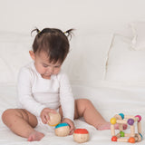 A baby playing with the Plan Toys Sensory Tumbling balls. The child is sitting on a bed. 