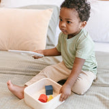Child lifting the lid of the PlanToys shape and sort it out bin wooden shape sorter toy.