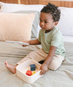 Child lifting the lid of the PlanToys shape and sort it out bin wooden shape sorter toy.