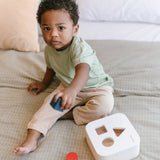 Child playing with the PlanToys shape and sort it out bin wooden shape sorter toy.