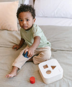 Child playing with the PlanToys shape and sort it out bin wooden shape sorter toy.