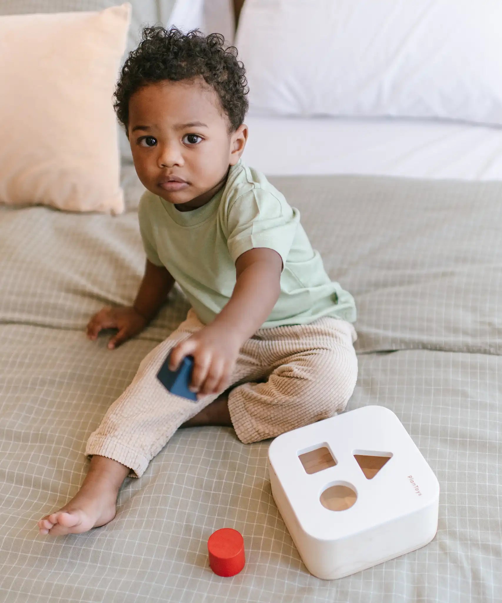 Child playing with the PlanToys shape and sort it out bin wooden shape sorter toy.