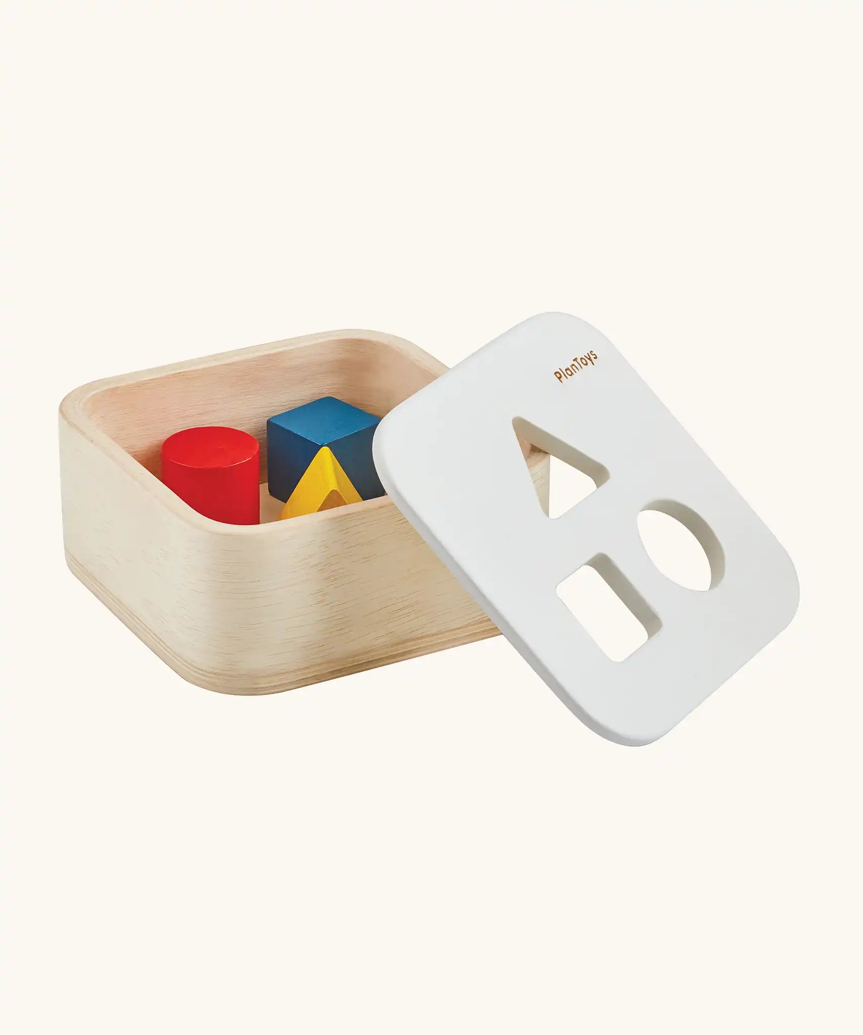 PlanToys shape and sort it out bin wooden shape sorter toy shown with the lid resting on the side. Square box with lid with three shaped holes in the lid. Yellow triangle, red cylinder and blue cube blocks.