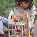 A child playing with the PlanToys Slide N Go Dolls' House, the pieces of furniture can be seen placed inside with PlanToys dollies. 