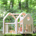 The PlanToys Slide N Go Dolls' House placed on a moss covered tree stump in the forest. 