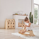 Young girl sat on the PlanToys children's palomino rocking horse on a white fluffy rug in a light playroom