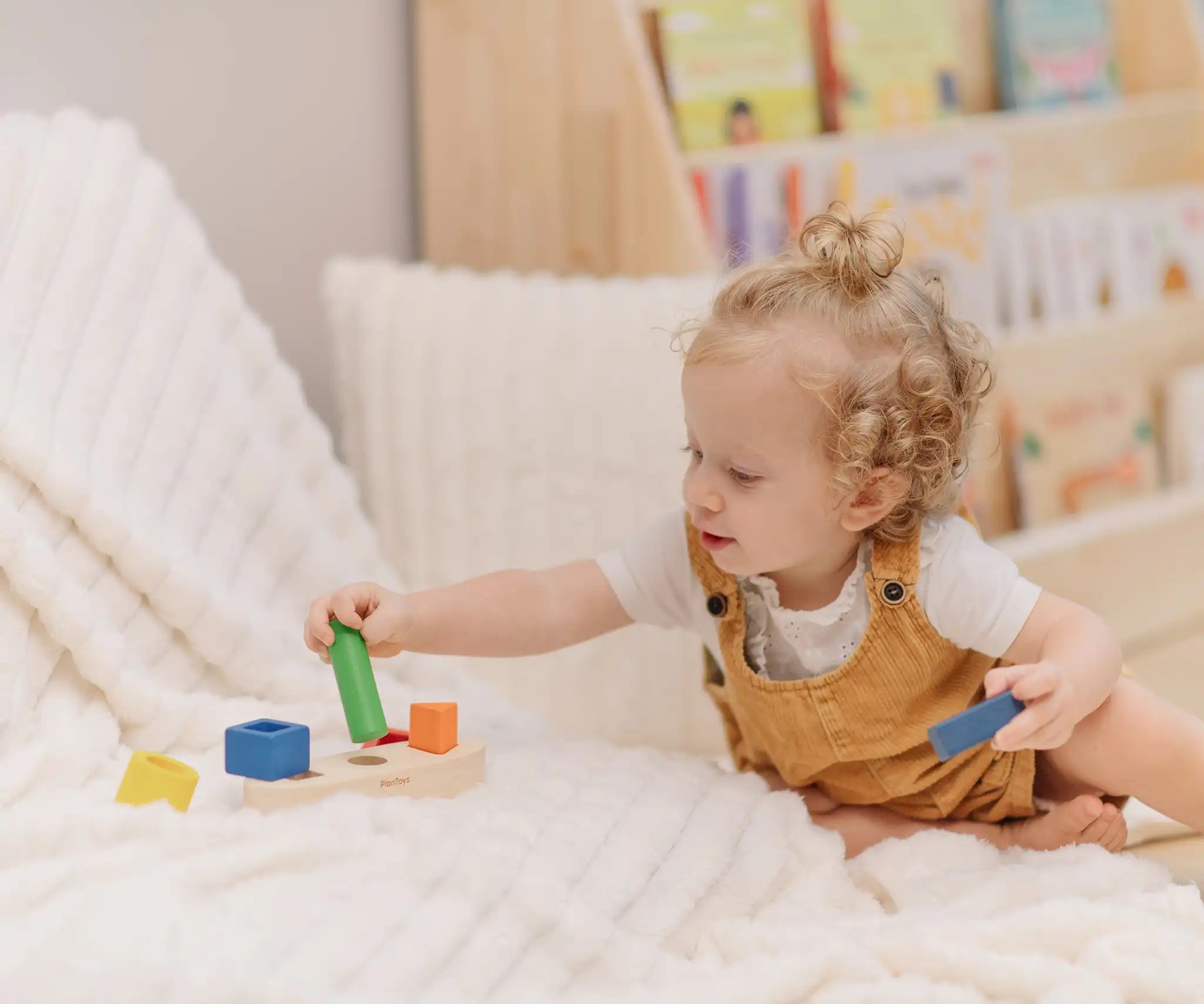 Child playing with the PlanToys sorting boat wooden shape sorting toy, placing the green cylinder onto the base frame.