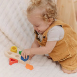 Child playing with the PlanToys sorting boat wooden shape sorting toy placing he blue square piece onto the base.