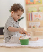 Child lifting up the PlanToys geo sorting bucket wooden shape sorting toy by the rope carry handle.